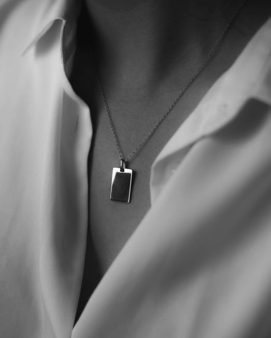 photo noir et balnc d'une femme en chemisier blanc portant un collier en argent 